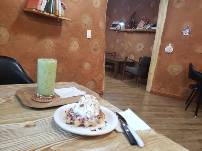 A glass of kiwi juice and a waffle on a table