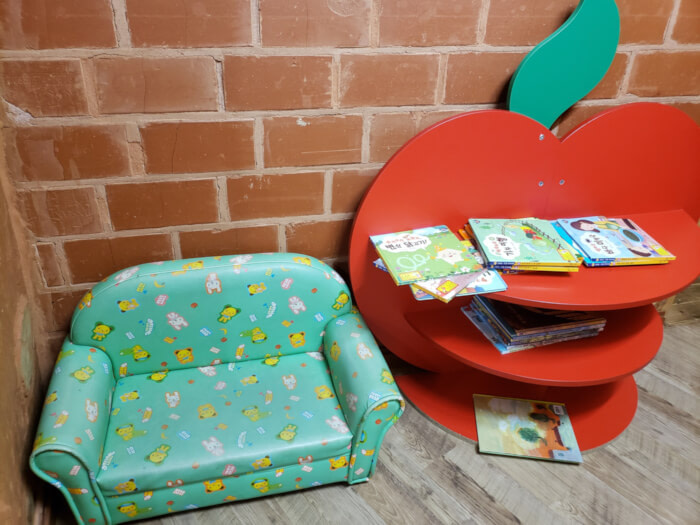 A nook for kids with a small couch and an apple-shaped table with books