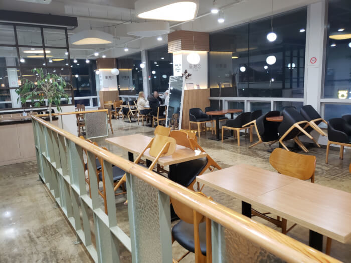 Interior of Taizen Café showing the railing where people line up for orders and tables are set up along the large windows