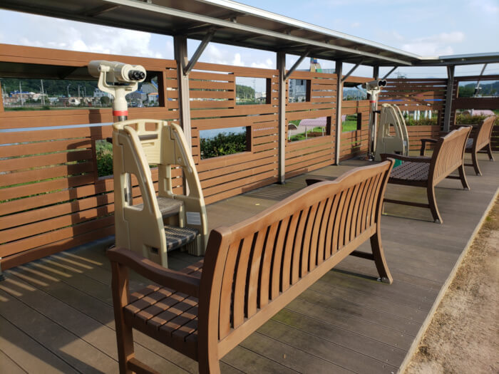 Bird watching station at Baegse Park with wooden benches and binoculars on a stand with stepladders for kids