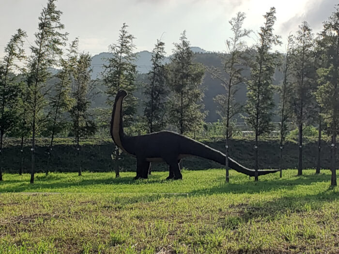 Dinosaur with a long neck in the grass at the park