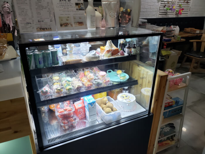 Rows of macaroons and a cake on display behind a glass counter