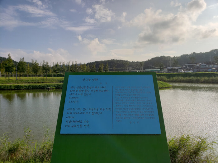 A metal plaque by the water with a Korean poem written on it