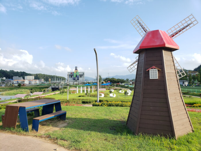 Picnic table next to the small windmill on a small hill overlooking the dinosaur play garden on a sunny summer evening