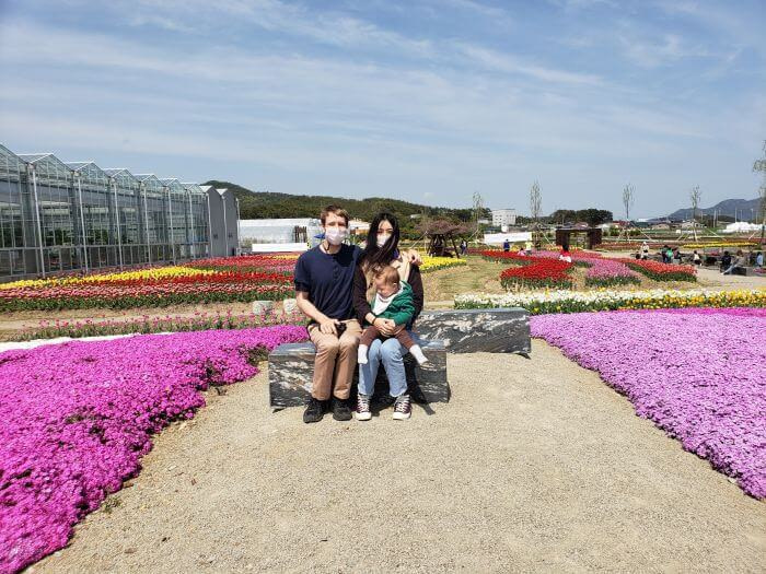 Nate, Alice, and Noah sitting on a rock between flowers at the Goseong Agricultural Technology Center