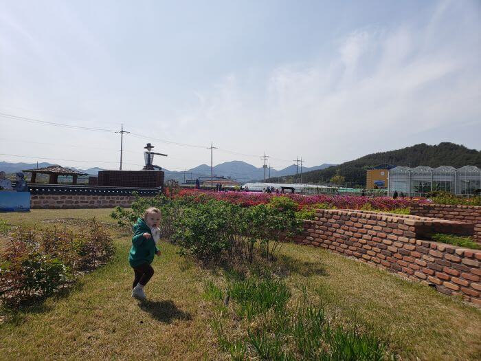 Noah walking in the grass between rows of plants at the healing herb garden