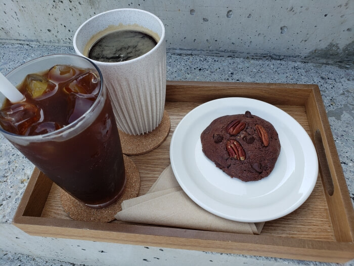 A tray of hot coffee, iced coffee, and a chocolate pecan cookie
