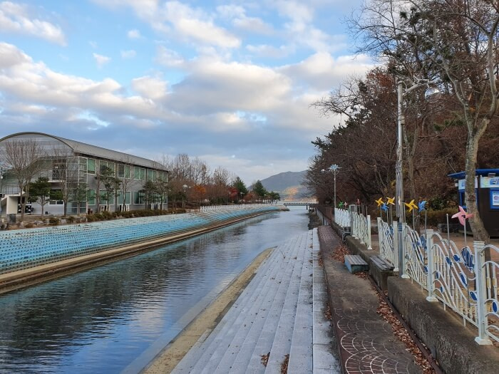 Looking over the side of the bridge at the water in the canal type of waterway bordered by stacked bricks on one end