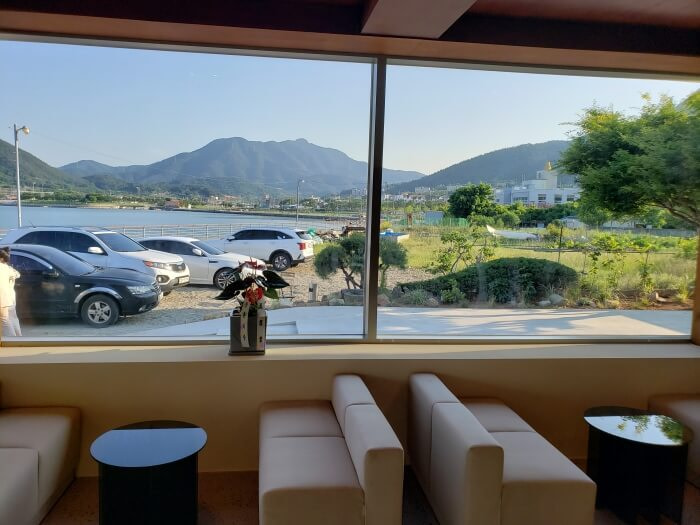 View of the sea and mountains out a window on the first floor with cushion seats