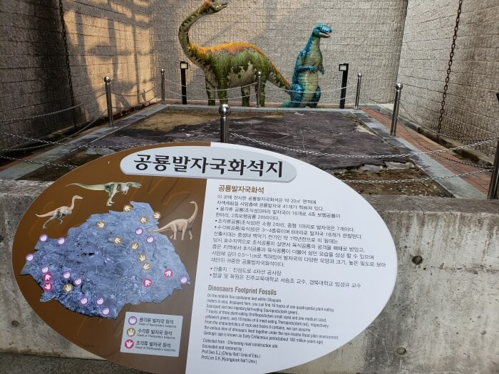 A dinosaur footprint fossil in a roped off section next a sign describing the prints and fossil trails
