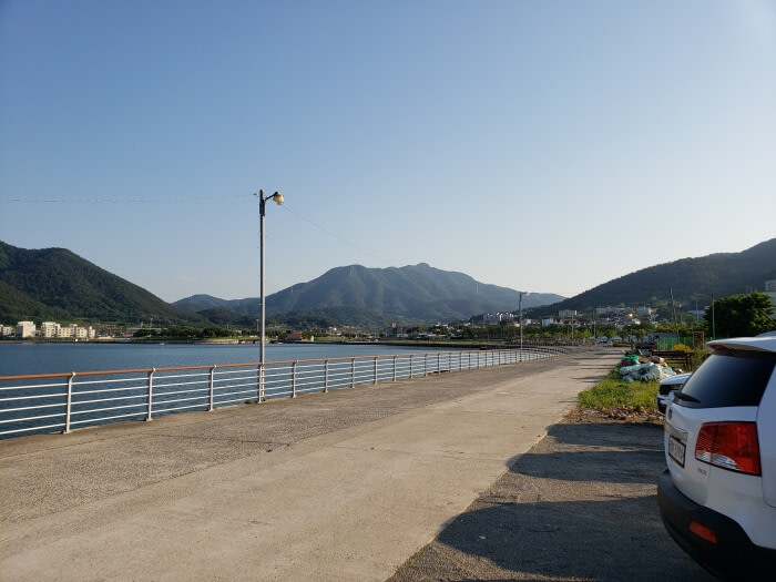 A long driveway along the sea surrounded by mountains