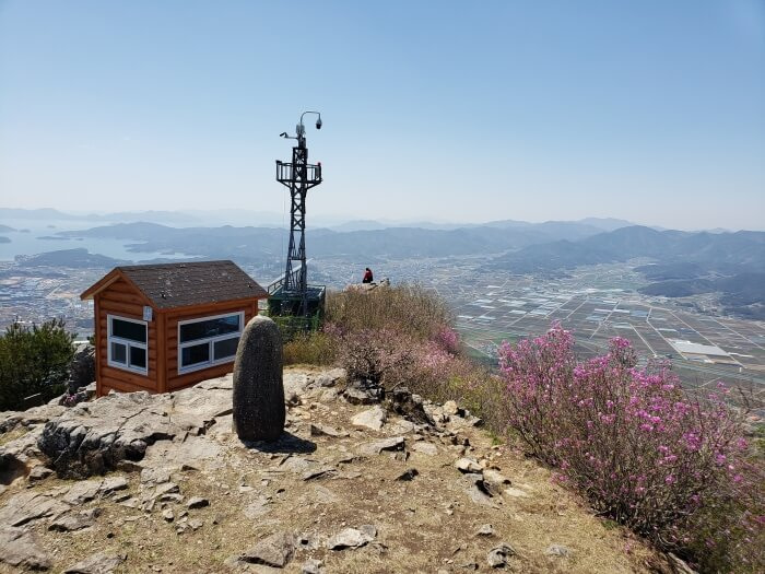 Peak of Georyusan showing the headstone, tower, and small shelter with pink flowering bushes