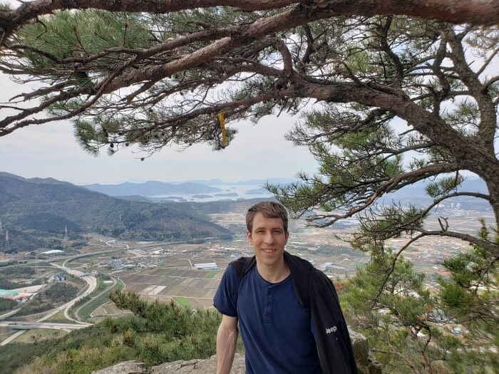 Nate under a pine branch sitting on a rock