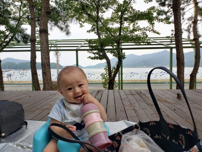 Noah chewing on a rubber handle on a wooden picnic platform near the sea
