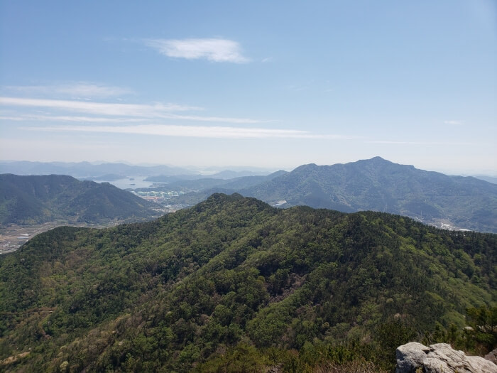 Other mountains in the distance covered with pines and other trees, with some water and islands visible