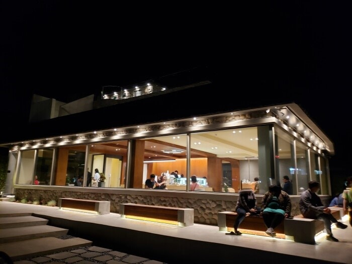 People sitting outside under the lights outside the café along with window