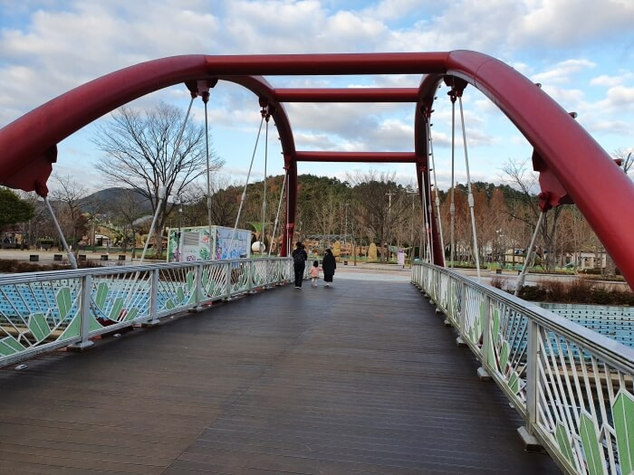 The small, red bridge with a wooden floor at the Goseong Dinosaur Theme Park