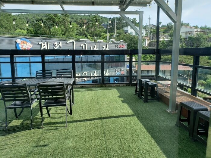 Table and chairs on the covered rooftop with a soft green floor