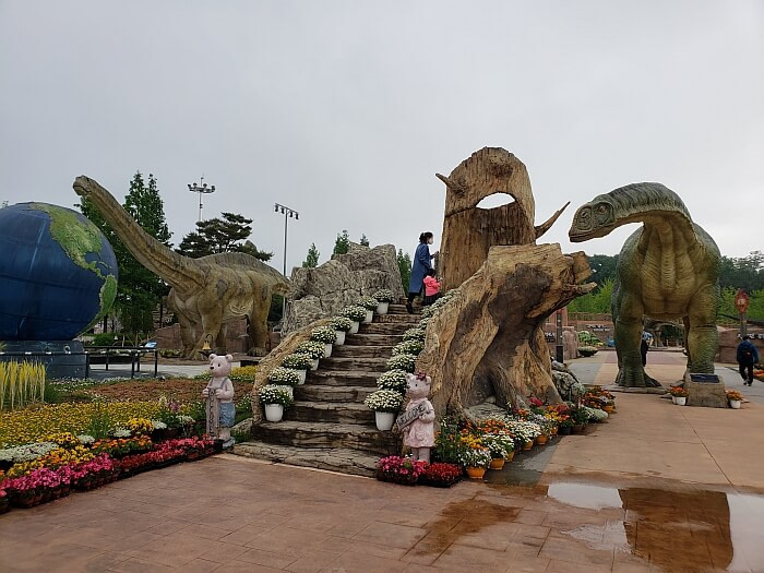 Stairs with flowers on both sides leading up to platform to get face to face with a dinosaur