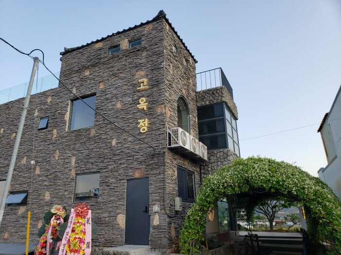 Stone building of Googjeong Cafe next to an archway of beautifully smelling flowers
