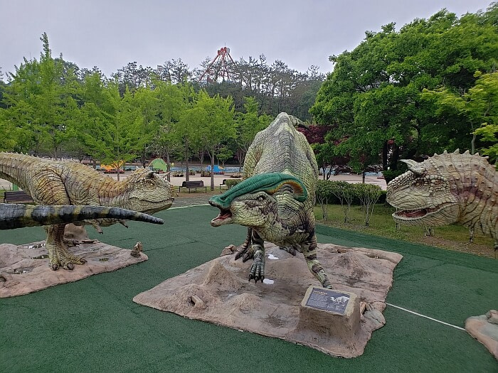 Various dinosaur posing next to each other in an area with a green turf