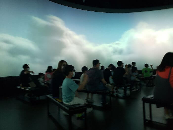 The 5D Experience Theater with clouds on the screen and seats filled with viewers