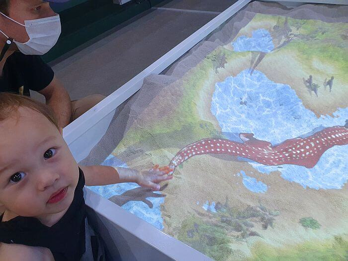 Baby Noah playing in the sand with images projected on the sand