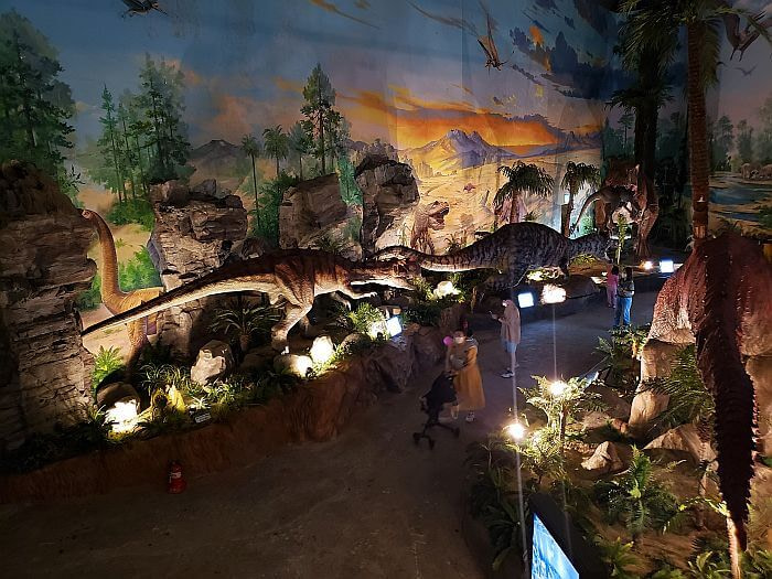 Dinosaur figures in a forest scene with painted walls and plants set up