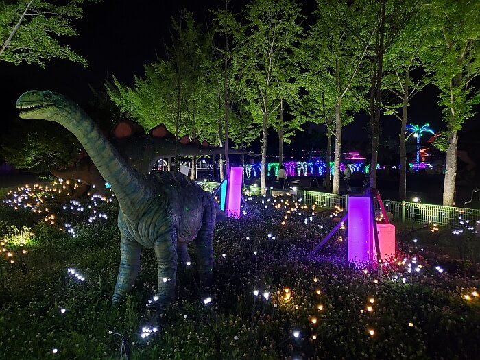 A dinosaur standing in the glowing grass at night