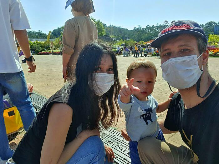 Family picture around the parade and dinosaur garden with Noah pointing toward the camera