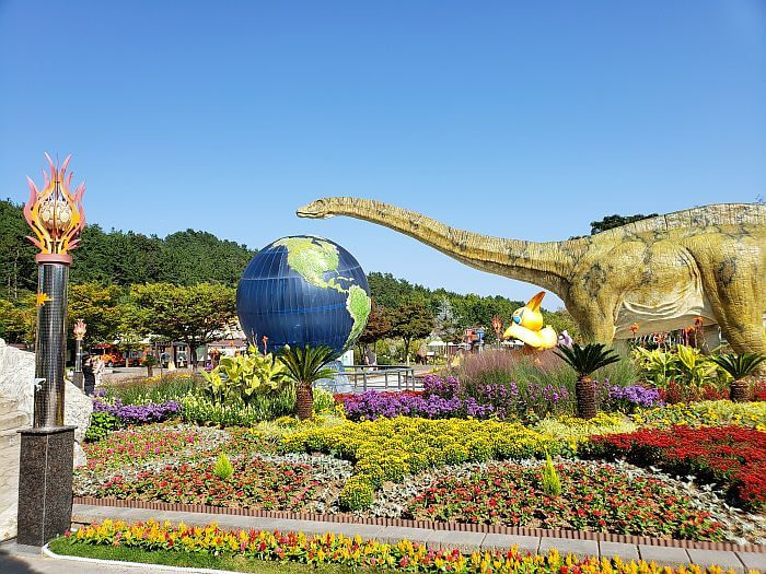 A long-necked dinosaur figure and globe with a garden of flowers of many colors