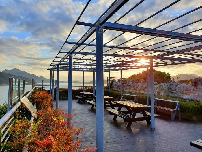 Sunset at the top of the Goseong Dinosaur Theme Park and World Expo overlooking the sea and mountains with picnic tables on a platform