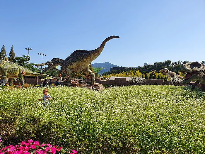 Noah almost hidden among flowering plants next to dinosaur figures