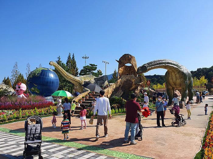 Parents and kids milling around in the outdoor dinosaur theme park