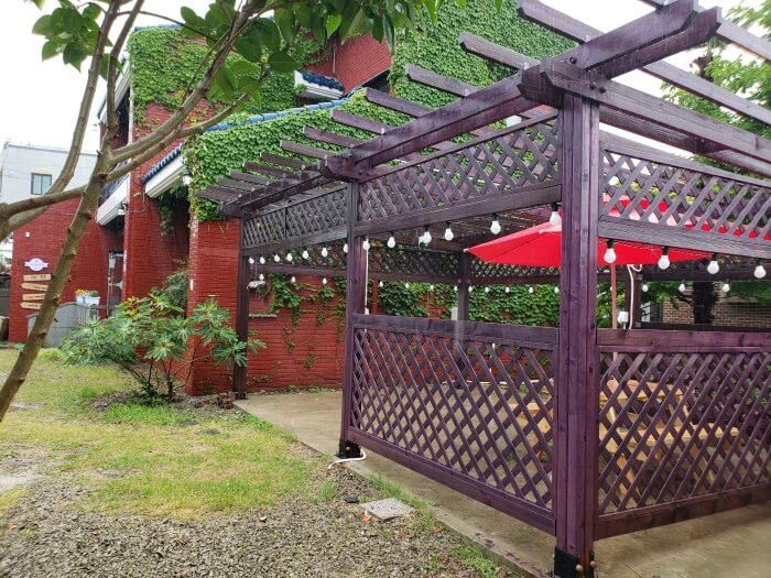 A picnic table enclosed by a lattice and lights overhead with an umbrella