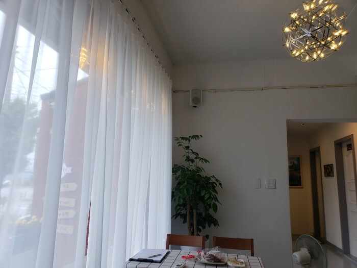 A large window with a white curtain and a stylish hanging light