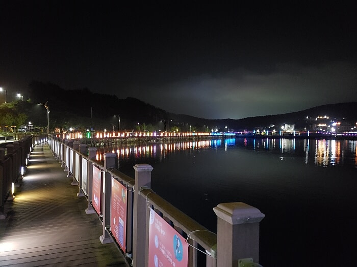 The boardwalk at night with lights reflecting off the water and mountains in the background