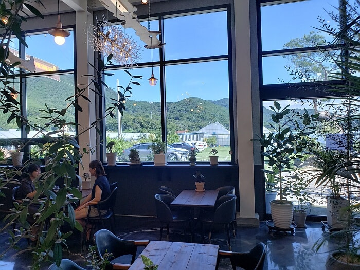 People sitting at tables along a window with mountains nearby