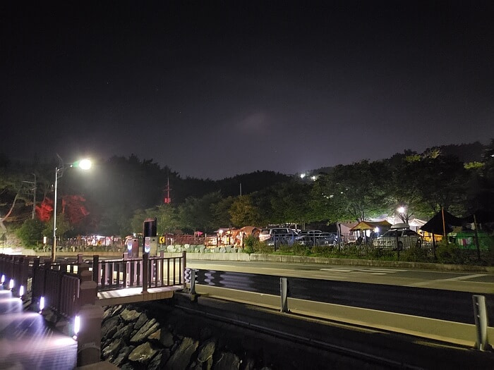 A full camping area across the street at night along the side of the road