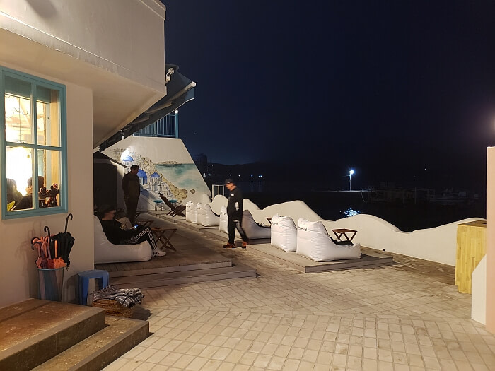 Cushiony chairs near a Greece mural on the wall at night