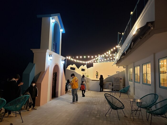 People enjoying Doors Café on the outdoor patio at night with lights stringed overhead
