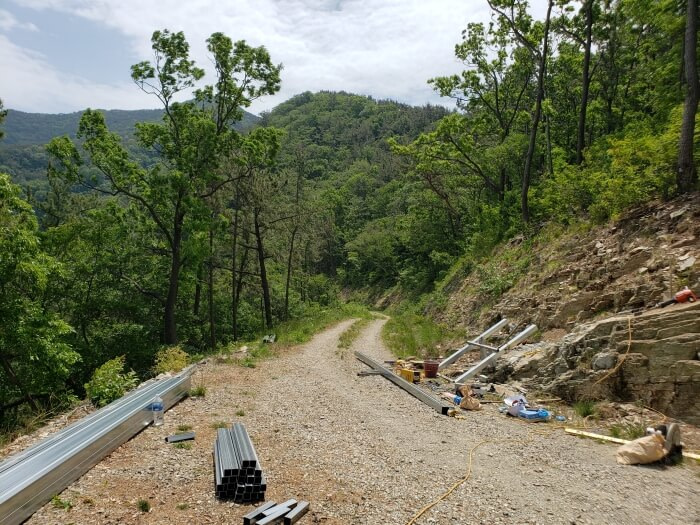 A gravel road winding around the mountain with minor construction materials along the sides for a small ramp