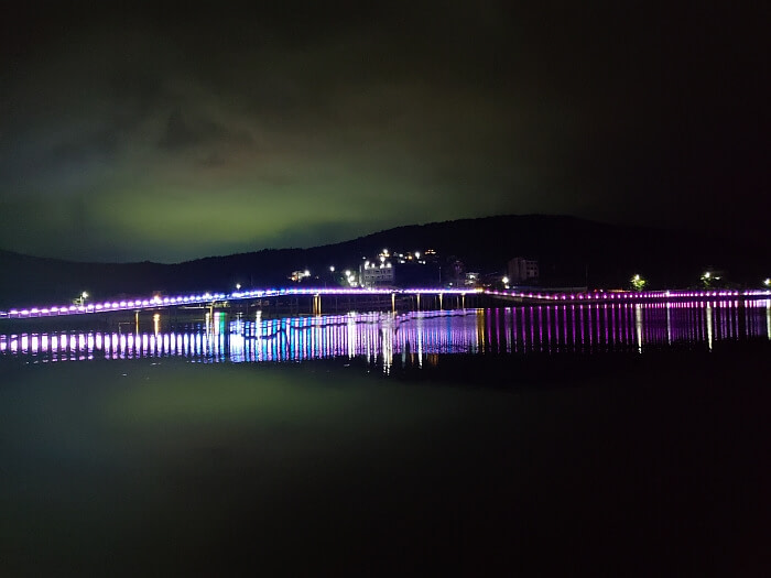 Purple and blue lights on Haejigae Bridge reflecting off the water at night