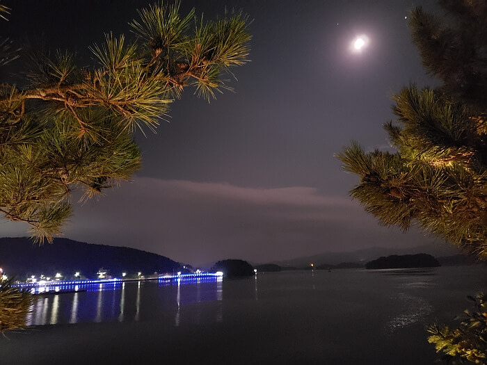 The moon shining over the water and the changing color of the lights from the boardwalk at night