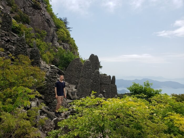 Nate standing against Byeogbangsan Rock structures against a nice view of the sea and islands and peninsulas