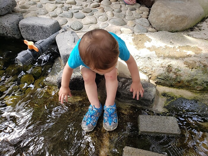 Noah sitting on a rock with his feet in the water