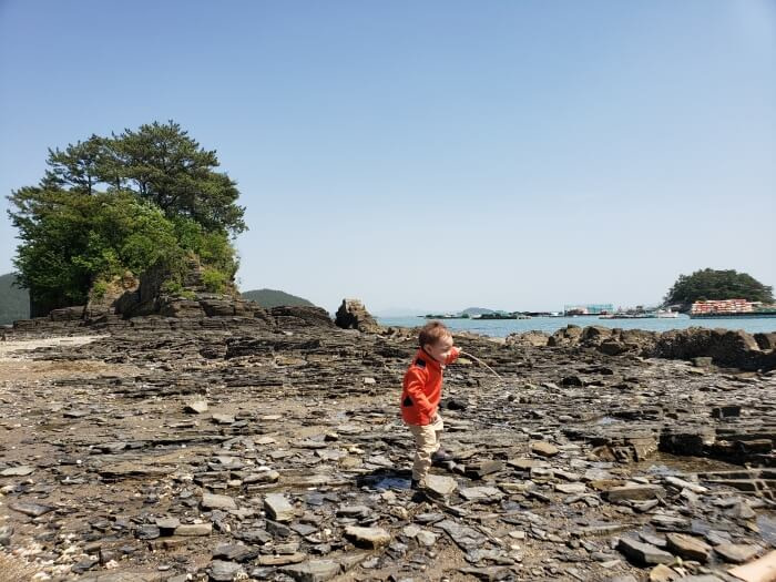 Noah walking on the rocky shore with a stick