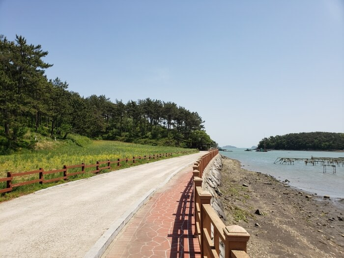 A paved path along the shore bordered by a fence leading to Solseom Island