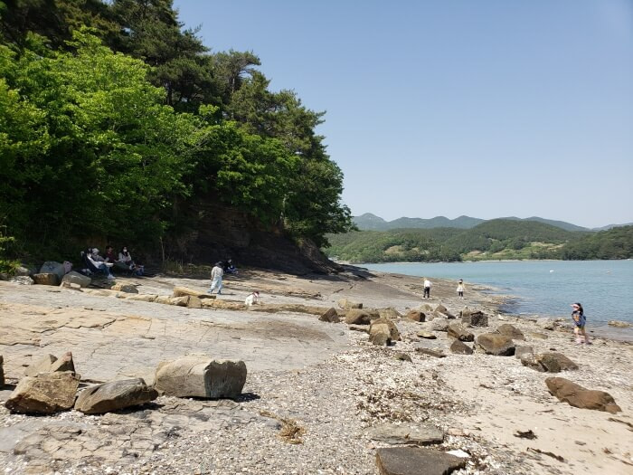 People walking along the shore with mountains in the background