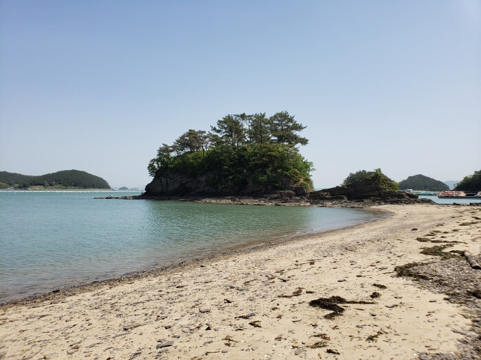 The sandy shore of Solseom Island with an outcropping with trees